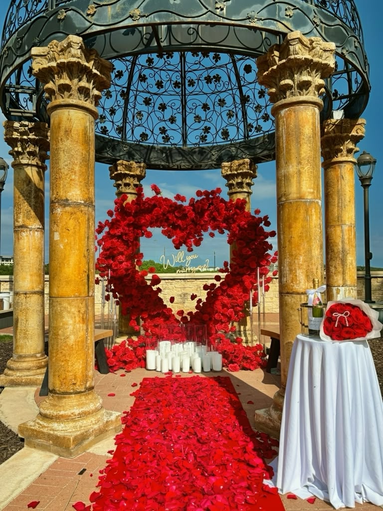 Rose heart arch proposal under a stone gazebo with red petal aisle by LUX Event Design