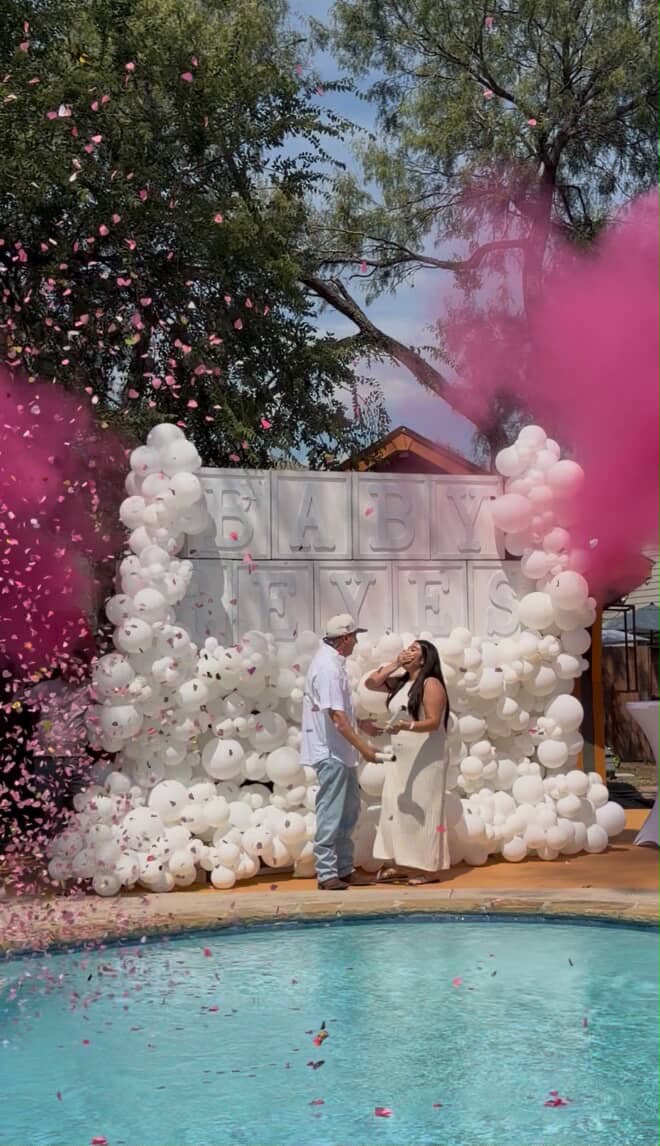 Outdoor poolside gender reveal with white balloon wall and pink smoke by LUX Event Design